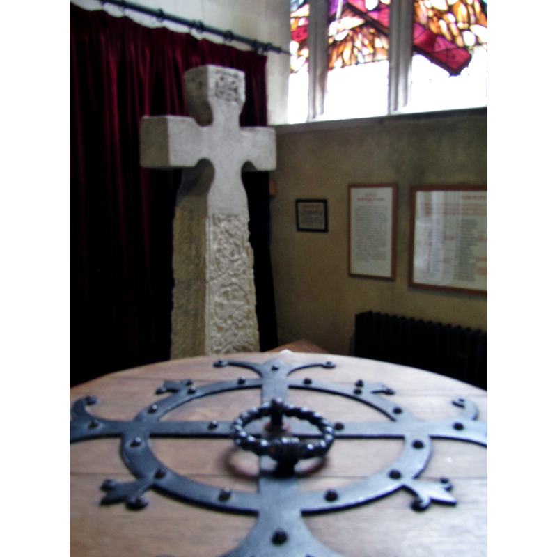 a modern cover on the Victorian font -- in the background is the restored Anglo-Saxon cross