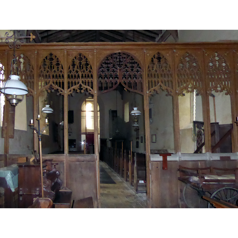 Source caption: "The screen of St Michael and St Felix Church, Rumburgh. When approaching from the west and passing remains of a moat and seeing the dominating west tower, it is realised that this is not a normal church. Indeed the church was not built as a parish church but as the church of a small Benedictine Priory. Aethelmaer,Bishop of Elmham, and Thurstan, Abbot of St Benet at Holme, jointly founded the priory between 1047 and 1064. It was a cell of Holme Abbey in Norfolk. Brother Blakere was the first prior. In 1070 the Bishop fell out of favour. The property was transferred to Count Alan the Red of Brittany who was a follower of William the Conqueror. On Alan's death, his brother gave Rumburgh Priory to the Abbey of St Mary in York. In the Domesday Book of 1086 it was recorded that 12 monks lived at the Priory. It was suppressed in 1528 and Cardinal Wolsey was granted the Priory's property and incomes. The plan of the church is Saxon with the broad west tower instead of a Saxon porch (according to Pevsner), and a nave and chancel of the same width. There are no aisles and no chapels. The west tower does dominate - it is wider than it is deep. It dates in its present form from the mid-13th century."