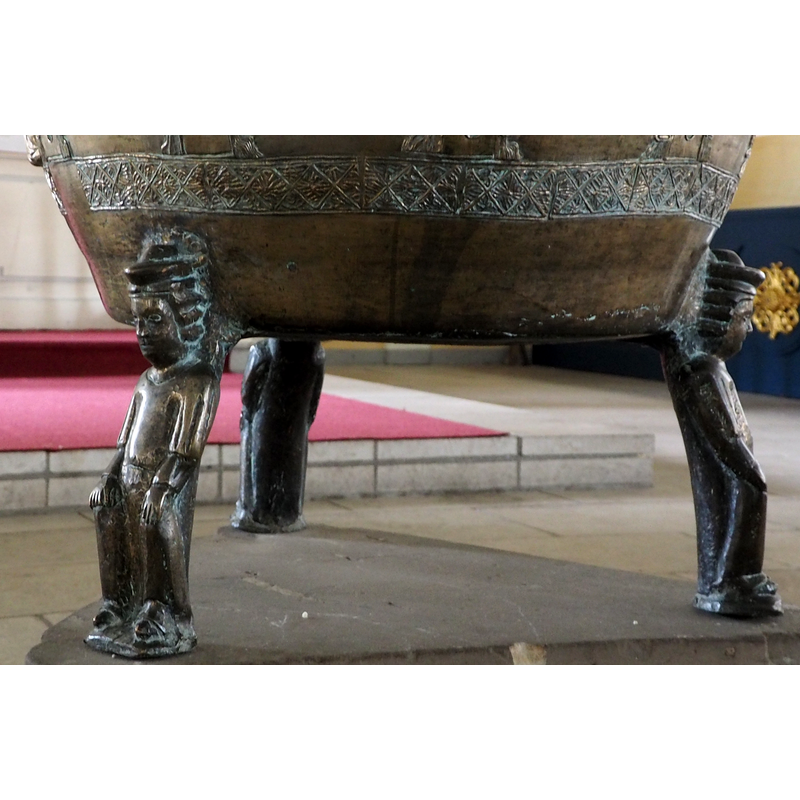 three figures, wearing hats and facing out, are set at 120-degree angles to support the basin