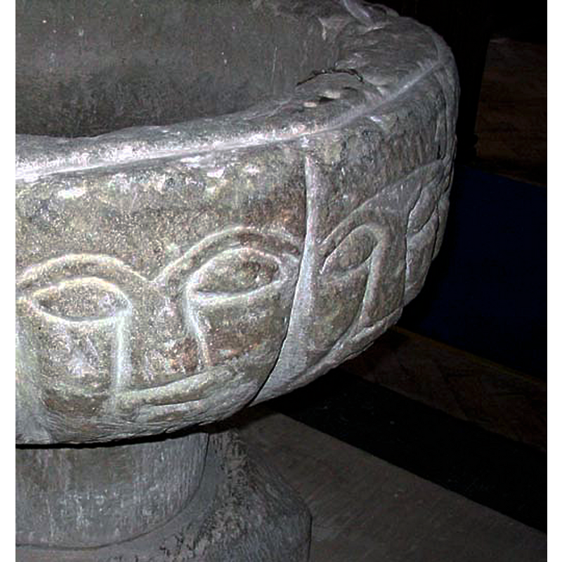 Source caption: "Late Norman Font Eglwys Llanwenog. There are twelve grotesquely shaped heads roughly carved around the font, they are thought to represent the twelve apostles."