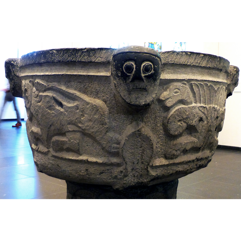 a large leaf beneath each of the four human heads on the basin sides