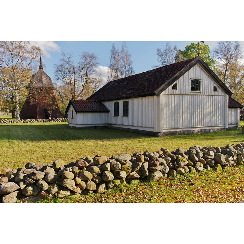 Source caption: "Kyrkan tillhörde Härjevads socken men står nu mer på Västergötlands friluftsmuseum i Skara." the old church seen here in its post-1921 location in the open-air museum; the tower of the old church was not moved with the 17thC church, probably because it was not original but a later addition; the bell tower or cote seen in the background of this photograph wa originally from Kärråkra kyrka, and would probably be similar to the original one at Härjevad's, if ever there was one there.