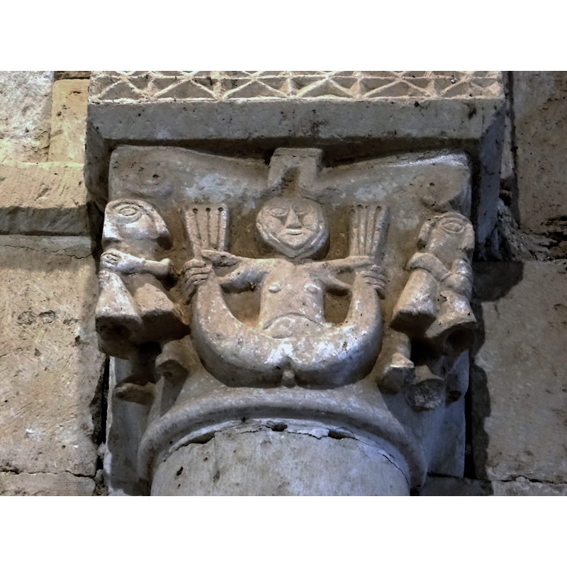 the siren holding its tails is also present in a capital of the apse window and in one of the capitals of the chancel arch