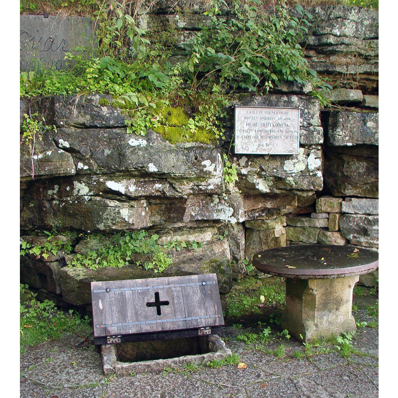 Source caption: "The well where Olov Skötkonung may have been baptized. Up left is a carving with the autograph of King Oscar II of Sweden. The sign reads "I källan här nedanför döptes omkring år 1000 OLOF SKÖTKONUNG Sveriges förste kristne konung af engelske missionären Sigfrid" ("In the well below the first Christian King of Sweden, Olof Skötkonung, was baptized around year 1000 by the English missionair Sigfrid")"