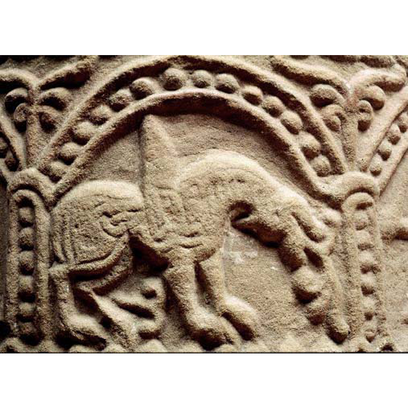 passant to the right -- if the 'hump' on its back is meant to be its wings, the animal would be a winged lion, as most of the other features would support that identification: the tail, seen here below, rather than above, is floriated, as is the long tongue issuing from its upside-down head -- like the other animals on this font, the mane appears to develop into an interlace, much eroded here