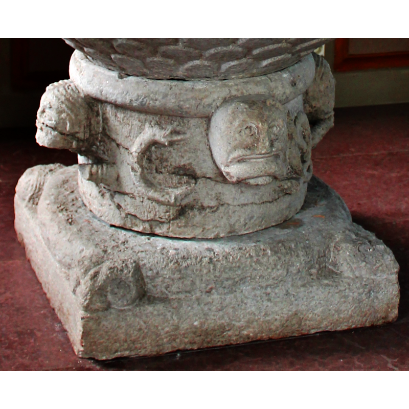 its body surrounds the stem of the base, tangles into interlaces and is bitten by the lion head