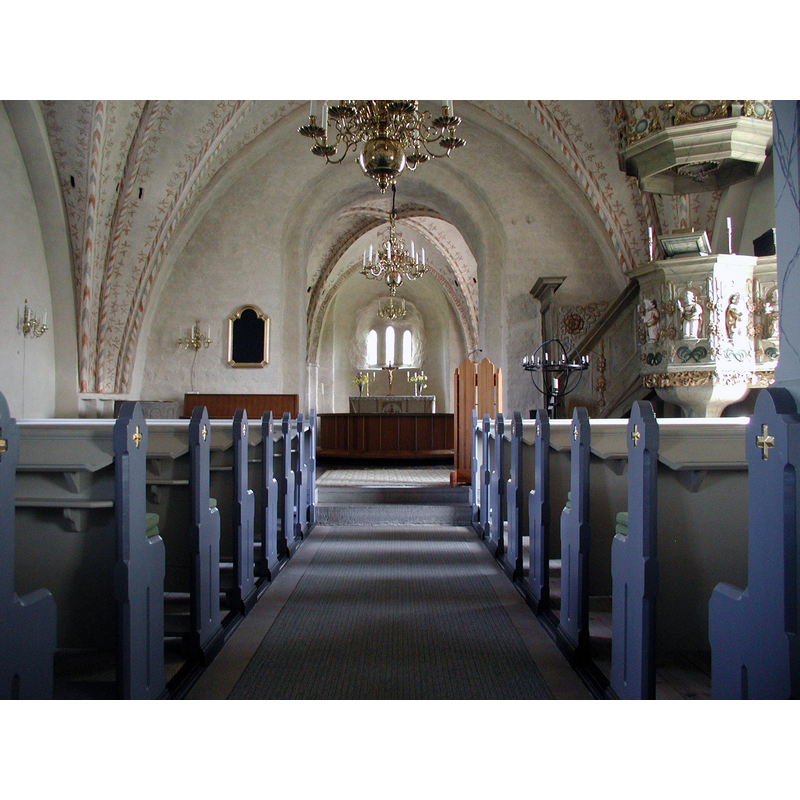 the top of the medieval font, now back in use with a metal baptismal dish, is visible at the far [east] end, left [north] side, by the north pillar of the chancel arch