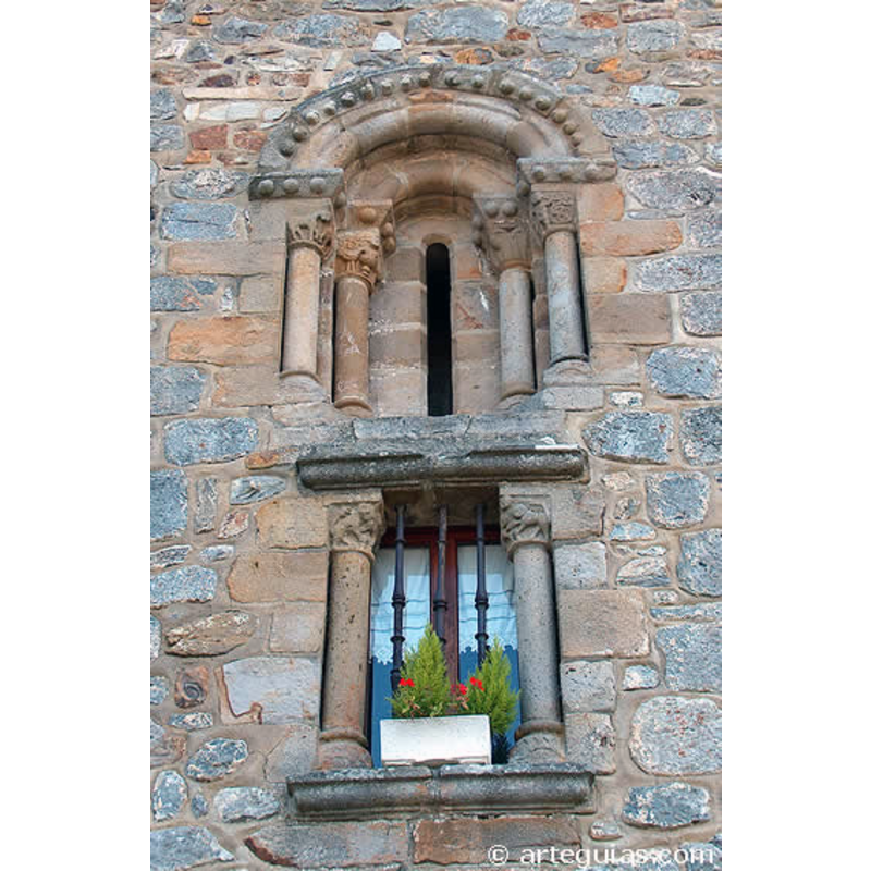 Source caption: "En la cabecera de la iglesia de Santa Eulalia de Bedoña hay dos ventanales románicos superpuestos, habiendo pedido el inferior todo el conjunto del arco sustituido por un arquitrabe, aunque han sobrevivido las columnas con sus capiteles. La iconografía del conjunto de los capiteles es bastante rica, aunque no así la calidad de la talla que se clasifica en una fase tardía y ruralizada. Los temas representados son diversos animales y el pecado de la lujuria."