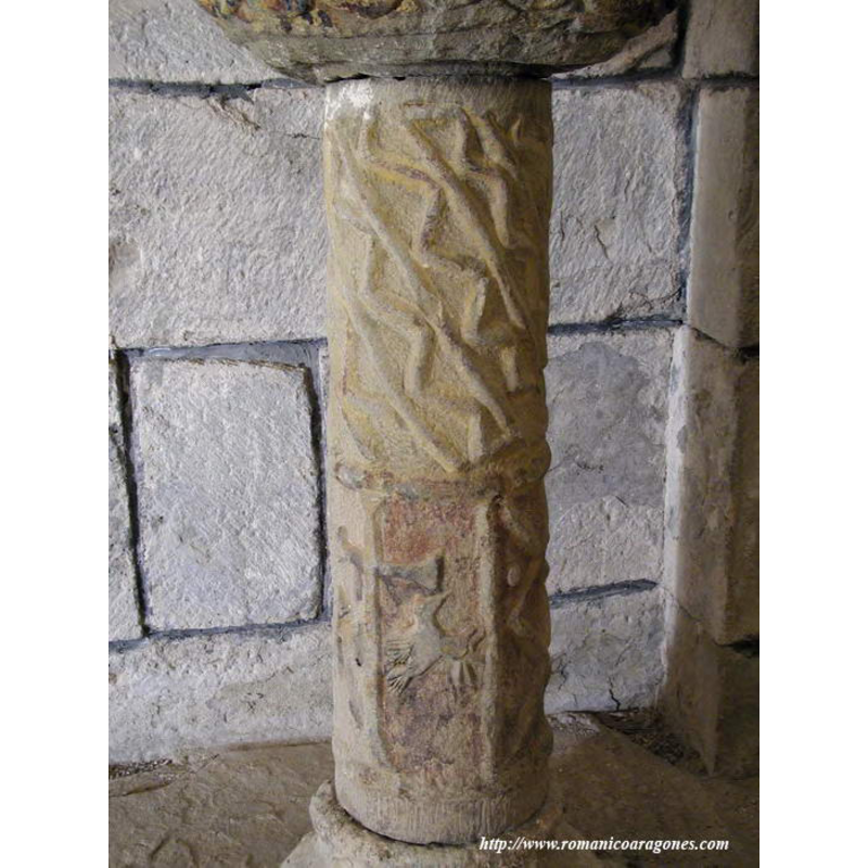 Source caption: "La base es una basa ática románica reutilizada; y entre ambas una columnita profusamente decorada, con zig-zag, una cruz, figuras toscas de aves, otra humana... Es tal el collage de esta "pieza" que me desconcierta. Hallo explicación en el libro "Detrás de Uruel" de D. Ricardo Mur: Data de 1546, fecha que está grabada en el pie ("D46"), y consta de una figura humana, una cruz flanqueada por dos caballos, motivos geométricos, y alrededor de la pila, motivos acuáticos."
