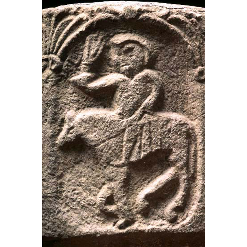 passant to the left; could be wearing a hat or helmet [or, big hair?]