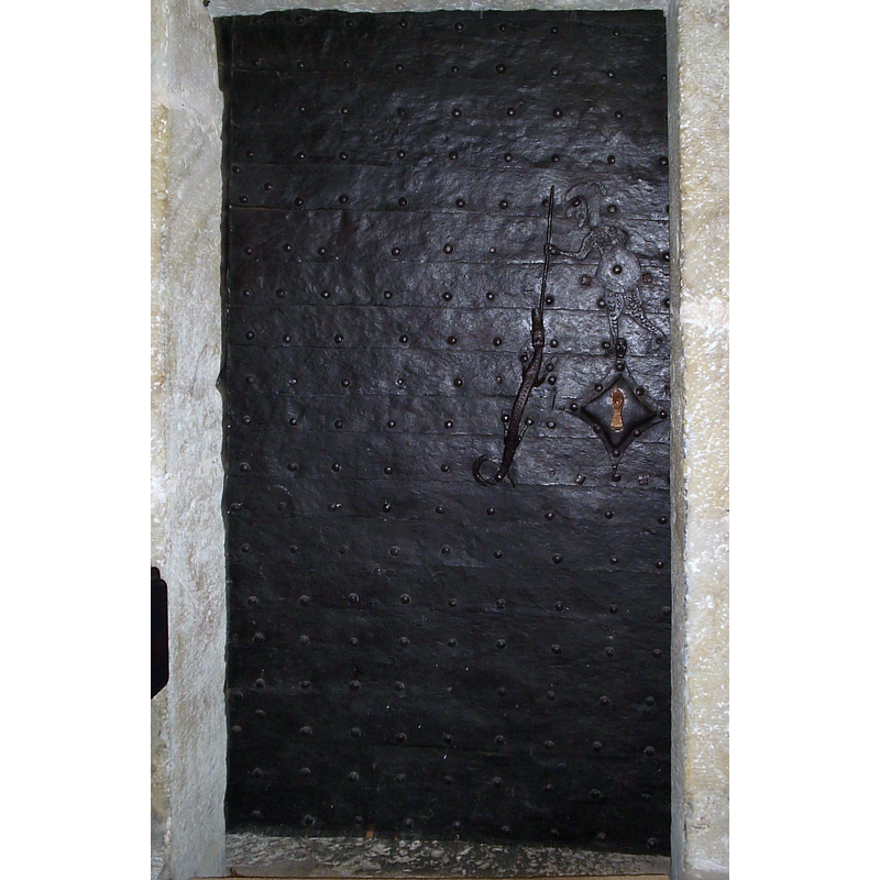 the 13thC(?) door into the sacristy -- Source caption: "Sakristians dörr har ett vackert handtag i järnsmide som föreställer Sankt Göran och draken. Utifrån modellen på riddarens hätta har man daterat dörren till sent 1200-tal. Nyckelskyltens övre spets är omformad till ett krönt huvud - prinsessans"