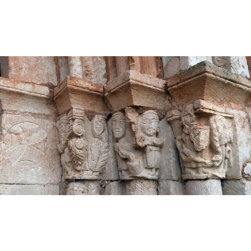 notice the Maltese cross inscribed in a circle to the left of the historiated capitals, a symbol that appears also on the font of this church -- Source caption: "Cruz paté, escena musical y de baile, herreros, y soldado luchando con dragón"