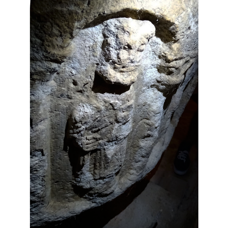 the object in the right hand is partly broken off, and tentatively identified here as a hissop of, more likely, a censer; the rectangular object close to the figure's chest appears to be a book -- notice also the capital in the top right angle of the image; only these three arches have carved capitals and bases, however damaged now