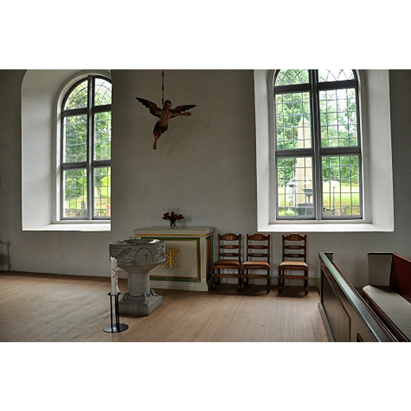 the 1940s font inside the 19thC church; the angel above is from the old church -- Source caption: "Dopfunt från 1945 under dopängeln som är kvar från gamla kyrkan"