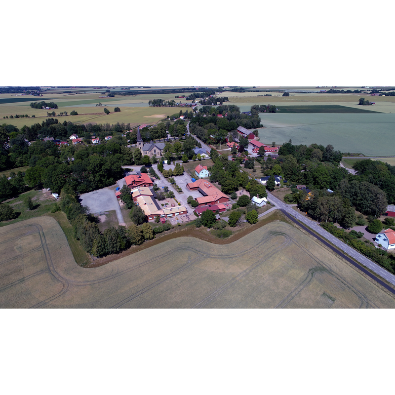 the new church of 1894 in context -- Source caption: "Saleby tätort i Lidköpings kommun från söder. Salebyskolan syns närmast i bild och Saleby kyrka strax bakom. Vägen till höger i bild är den mellan Jung och Lidköping."