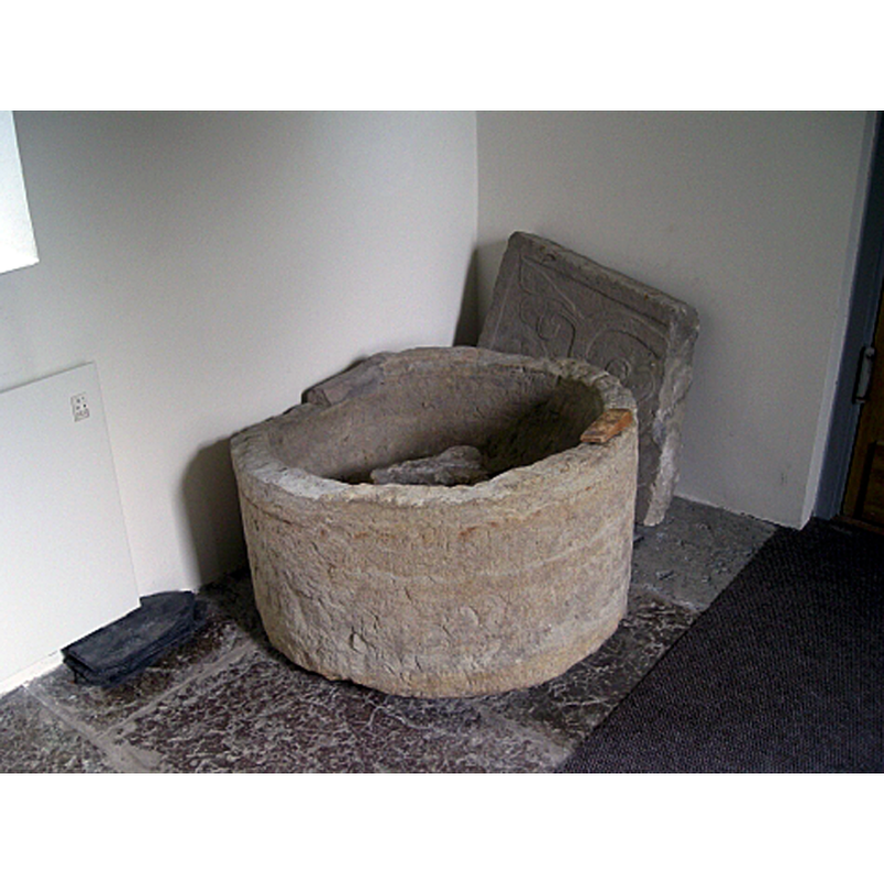 the damaged basin of the medieval font recovered from the old church, now disused in the new church, at the west end, by the entranceway