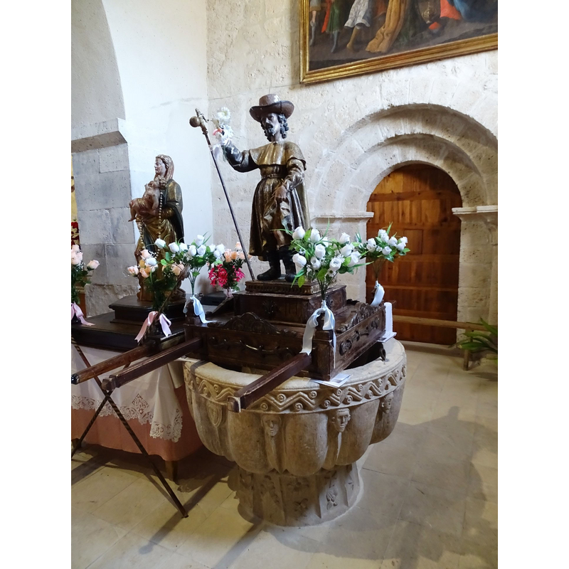 the wooden object on the font is not a font cover, but a float; the statue must be St. Roch, identified in the Golden Legend; became very popular during the plagues all over Europe; usually depicted showing his leg wounds, which a dog would lick to healing -- very dapper here in his 'French' hat here