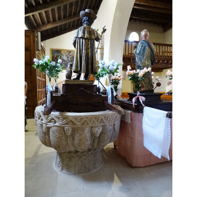 the wooden object on the font is not a font cover, but a float; the statue must be St. Roch, identified in the Golden Legend; became very popular during the plagues all over Europe; usually depicted showing his leg wounds, which a dog would lick to healing -- very dapper here in his 'French' hat here