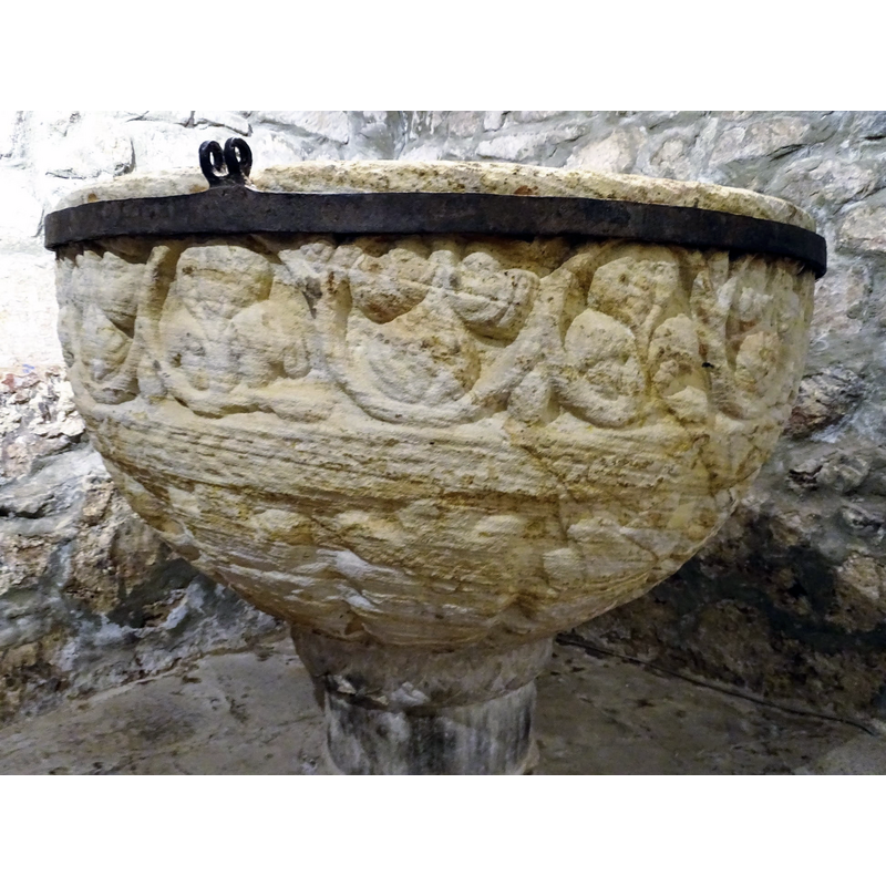 with very large leaves, all around -- the metal cinch appears to have been installed with a dual purpose: to reinforce the fragile basin and to provide anchorage for an old font cover that is no longer in place.