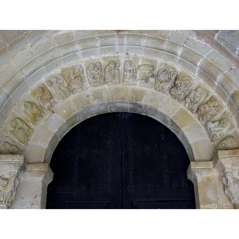 Source caption: "En la portada románica de la iglesia de San Miguel existe una representación de los meses del año por medio de escenas agrícolas correspondientes a los mismos; estas escenas están cinceladas en las dovelas que forman el arco de entrada a la iglesia. El hecho de que haya estado la portada dentro del atrio porticado, protegiéndola de la intemperie durante siglos, ha sido la razón por la cual ha llegado a nosotros en un estado de conservación bastante aceptable. El conjunto de estas escenas recibe distintos nombres, algunos dicen mensuario o mensario, otros lo llaman menologio, y otros calendario agrícola que es el que más propiamente lo define. Sus catorce relieves de la arquivolta, los que con su color están pidiendo ser colocados en el lugar interpretativo que les corresponde. Y esto se sale por completo del reducido ámbito de la región y el pueblo de Beleña, para entrar de lleno en la ancha corriente histórica que nace en el mundo pagano de la península Itálica y cuaja finalmente en el crisol medieval de la Europa cristiana. De esta expresión artística, que no es muy corriente, se conservan varios calendarios en España; unos están esculpidos en piedra, como el de la iglesia de Beleña. Otros son pinturas al fresco, como el de San Isidoro de León; y otros están bordados, como el del Tapiz de la Creación (parcialmente conservado) que se custodia en la catedral de Gerona. También se puede encontrar alguno en otros países, como en Francia, en Italia,"