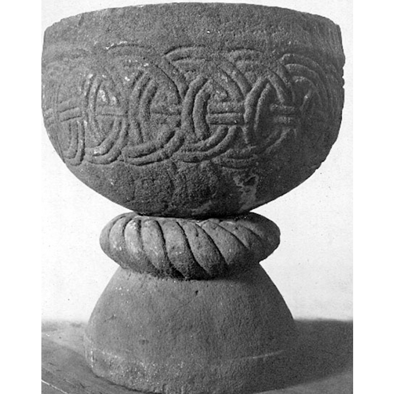 Source caption: "Dopfunt av sandsten med uttömnigshål. H. 94 cm. B. 81 cm. R. 64 cm. Dj. 36 cm. Veckholm. Den halvfsfäriska cuppan ornerad med i varandra trädda ringar genomdragna av ett band. Över den halvsfäriska foten en repstavsvulst. - Engelskt påverkad skola från 11000-talets förra hälft."