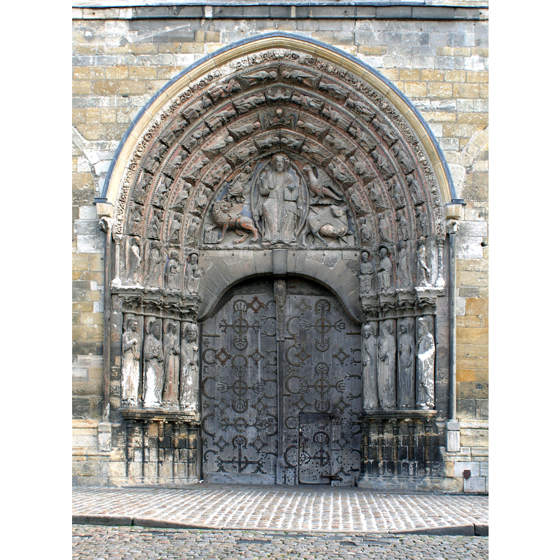 Source caption: "Portail occidental de la cathédrale d'Angers. Statues-colonnes dans les ébrasements, personnages (anges, musiciens) dans les voussures de l'archivolte, Christ en mandorle entouré du symbole des quatre évangélistes tétramorphe dans le tympan. Traces de polychromie. Linteau en arc en doucines affrontées. Porte à deux vantaux à pentures et fausses-pentures, guichet dans le vantail de droite."