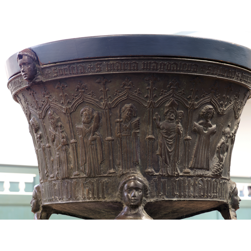 Source caption: "Gotisches bronzenes Taufbecken gegossen von Hinrich Klinghe in der ev. reformierten Kirche in Uttum (Ostfriesland) aus dem Jahr 1472. Ansicht von Nordwest. [NB: the orignal filename includes "baptismal_font_northwest_side" in it,but the font appears to be on a platform on casters, which would make the orientation meaningless in the canonical sense]