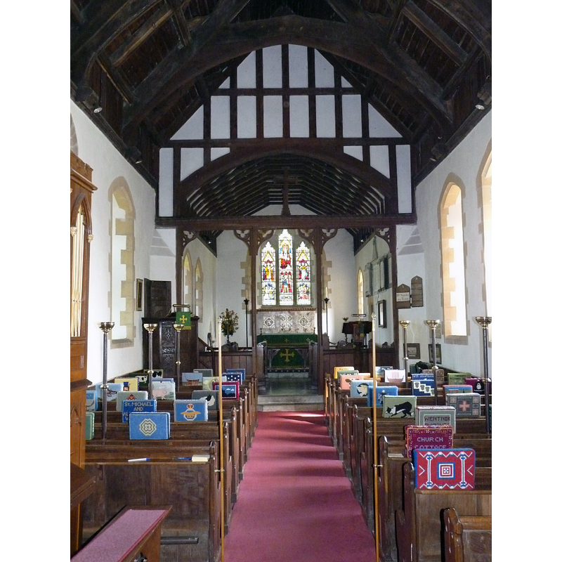 Source caption: "The nave of the church. The interior of the church of St Michael and All Angels, with its oak seats and choir stalls, a mosaic-worked reredos and oak pulpit, dating back to James I."