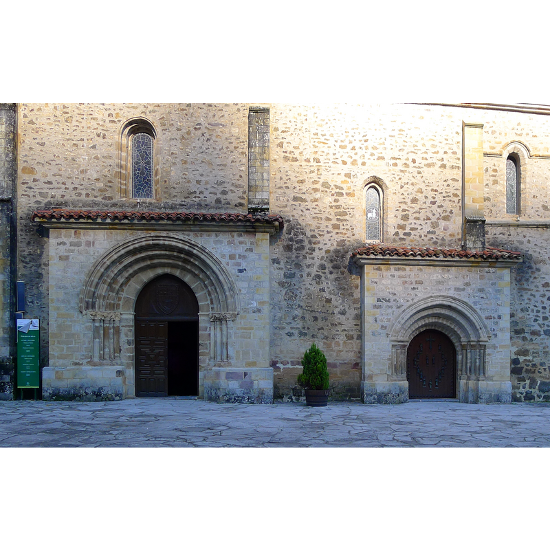 Source caption: "Fachada meridional (1256). La fábrica gótica presenta dos puertas, que sobresalen del muro. Su hechura románica ocasiona el debate de los especialistas, por manifestar algunos la procedencia del anterior monasterio románico."