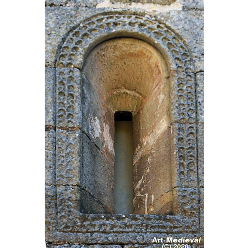 Source caption: "Destaca la ventana del ábside, de un solo derrame. Se abre en la parte central del muro este y presenta un arco de medio punto, con una cenefa hecha con un tallo de la que salen hojas, que la rodean totalmente."