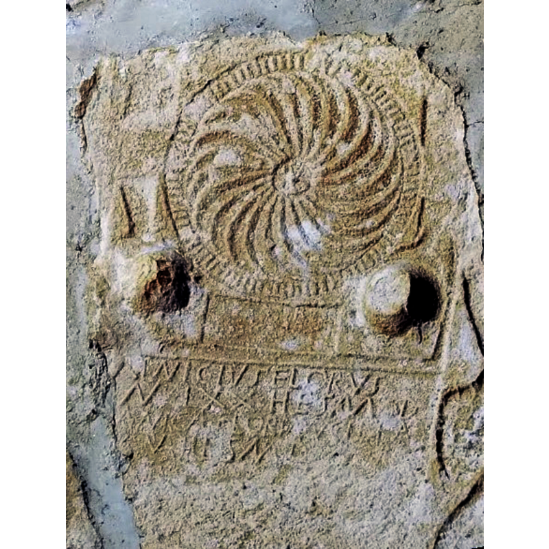 Source caption: "Hilarri erromatarrak Kontrastako Elizmendiko baselizan. Alboz jarrita daude paretetan." [NB: the former Hispano-Roman funerary monument of an old man, Minicius Florus, and his child slave was re-cycled in the medieval Ermita de Elizmendi, in Contrasta]