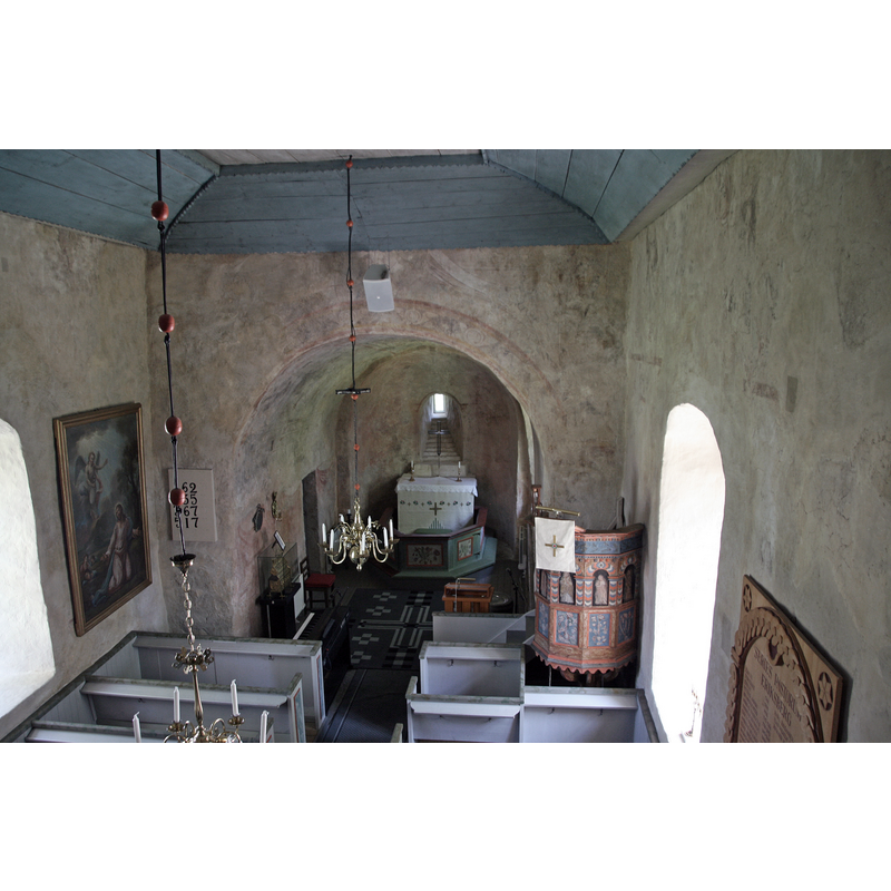 the interior of the old church showing some of the medieval murals uncovered in the 1949 renovation; the baptismal font is partially visible to the right of the lectern