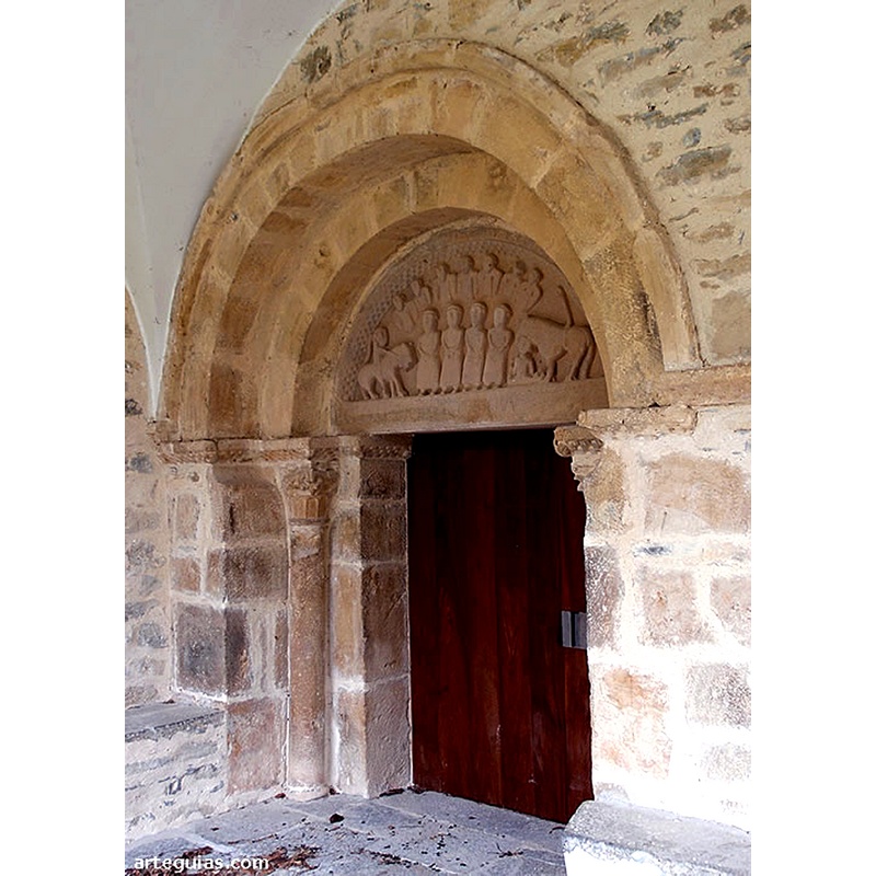 "El otro elemento románico de la iglesia es la portada. Ésta no se encuentra en su ubicación original, sino que fue trasladada cuando se rehicieron los muros del edificio, siendo difícil vaticinar el lugar en el que se encontraba en tiempos medievales. En la actualidad se sitúa en el costado de la epístola, protegida por el pórtico construido en época moderna.