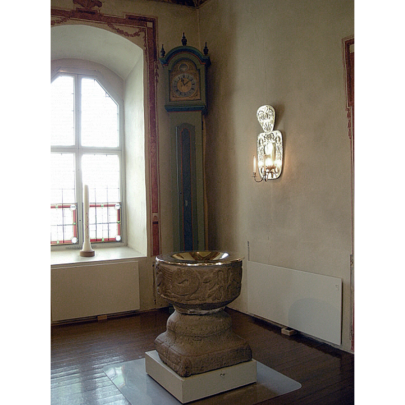 the medieval font in the southeast corner of the church, between the communion railing (in the foreground) and the southeast priest's or chancel entranceway (in the background) [NB: the plinth is modern and may be on casters]