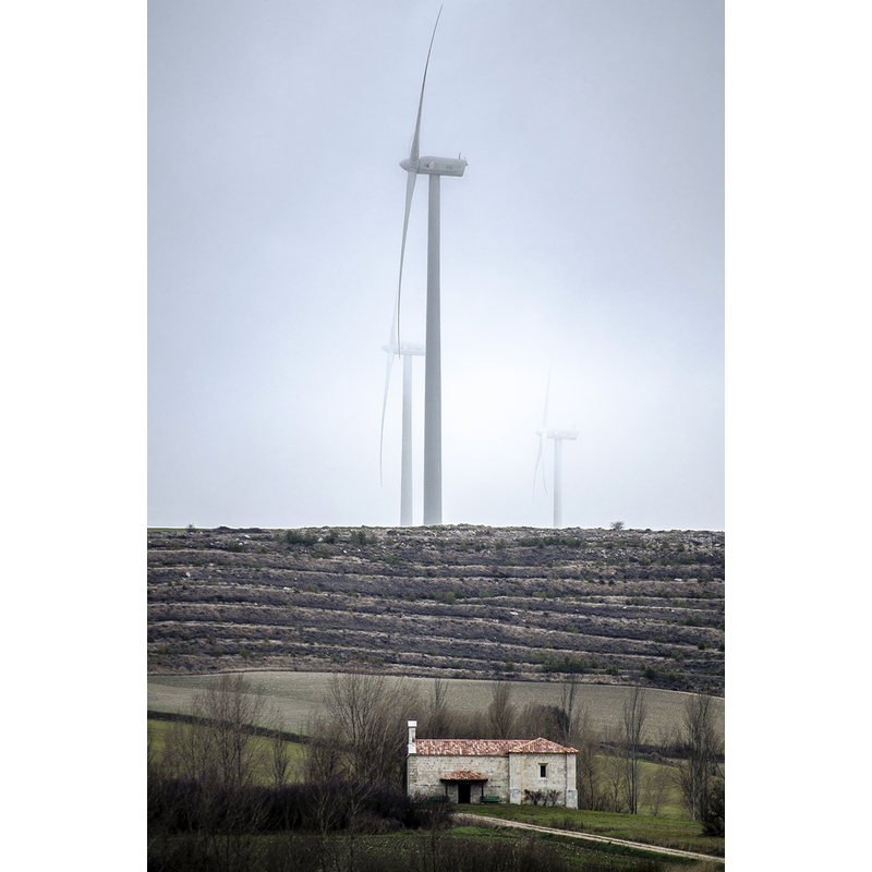 the rural chapel dwarfed by the wind mills