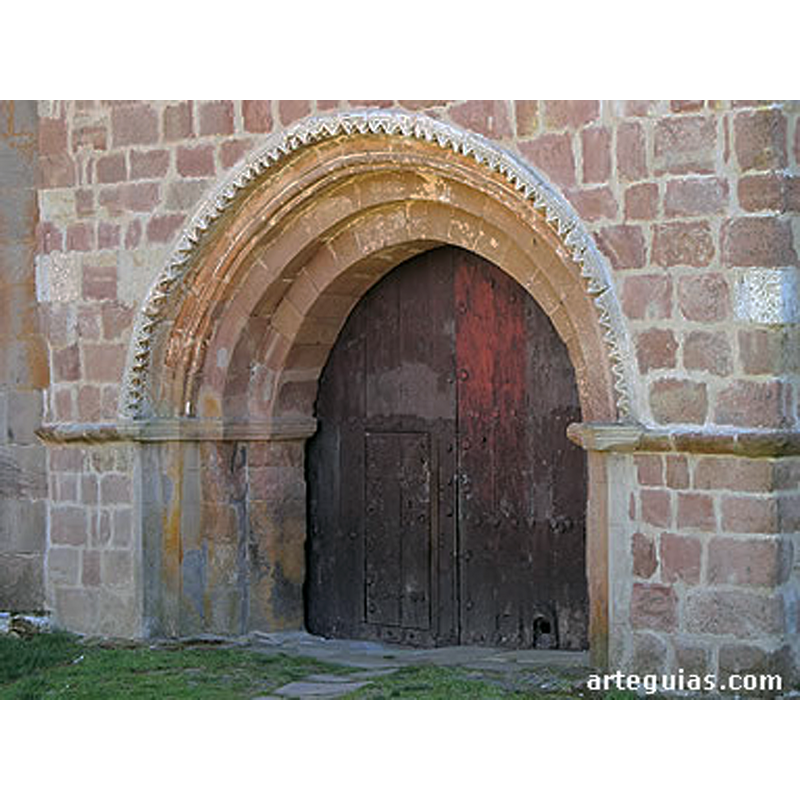 Source caption: "La del costado norte sí es visible, siendo mucho más sencilla con arquivoltas de medio punto sobre jambas -sin columnas- y un guardapolvos con puntas de diamante, lo que delata su carácter tardío."