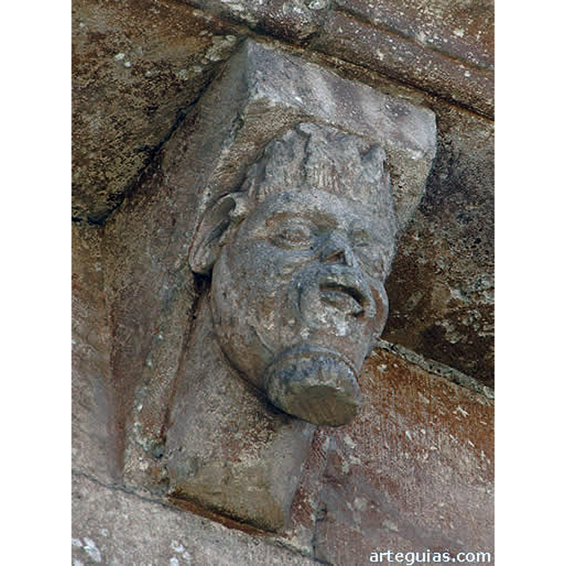 Source caption: "La colección de canecillos de esta iglesia de Arlanzón es muy original y expresiva, además de conservarse muy bien [...] También mencionamos un canecillo con una cabeza de rasgos negroides, perilla, además de cabello encrespado y algo rizado (como imitando llamas) y que se nos antoja como una representación de un musulmán o del mismísimo diablo."