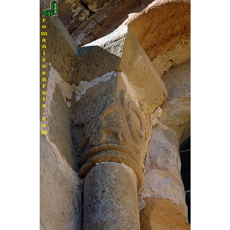 Source caption: "La ventana central del ábside [...] presenta dos arquivoltas, una exterior sencilla y otra interior de baquetón. El cimacio es liso y se apoya sobre los capiteles de las dos columnas. El capitel izquierdo [...] y en él parece que una culebra muerda una de las pinzas de un crustáceo."