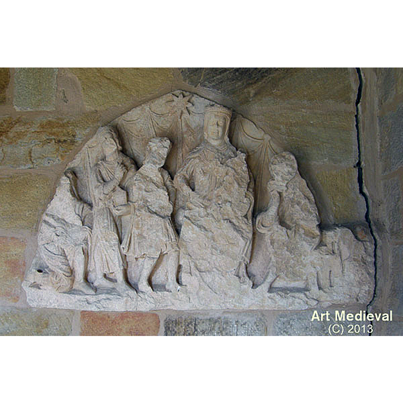 Source caption: "En el pórtico de entrada encontramos una de las piezas más importantes, que conserva este templo. Se trata de un tímpano gótico donde se representa la Epifanía. Se cree que formaba parte de una desaparecida portada románica tardía, que probablemente se abría en el mismo lugar que la actual. Representa la adoración de los Reyes, que están colocados a la izquierda de la Virgen con el Niño y San José a su derecha medio dormido. Sobre ellos está la Estrella de Belén. Desgraciadamente está en muy mal estado, pues está muy erosionada. A pesar de ello podemos ver una excelente manufactura, especialmente en la cara de la Virgen."