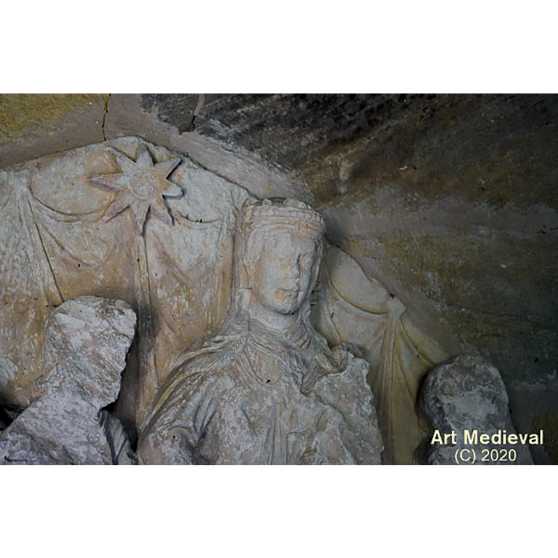 Source caption: "En el pórtico de entrada encontramos una de las piezas más importantes, que conserva este templo. Se trata de un tímpano gótico donde se representa la Epifanía. Se cree que formaba parte de una desaparecida portada románica tardía, que probablemente se abría en el mismo lugar que la actual. Representa la adoración de los Reyes, que están colocados a la izquierda de la Virgen con el Niño y San José a su derecha medio dormido. Sobre ellos está la Estrella de Belén. Desgraciadamente está en muy mal estado, pues está muy erosionada. A pesar de ello podemos ver una excelente manufactura, especialmente en la cara de la Virgen."