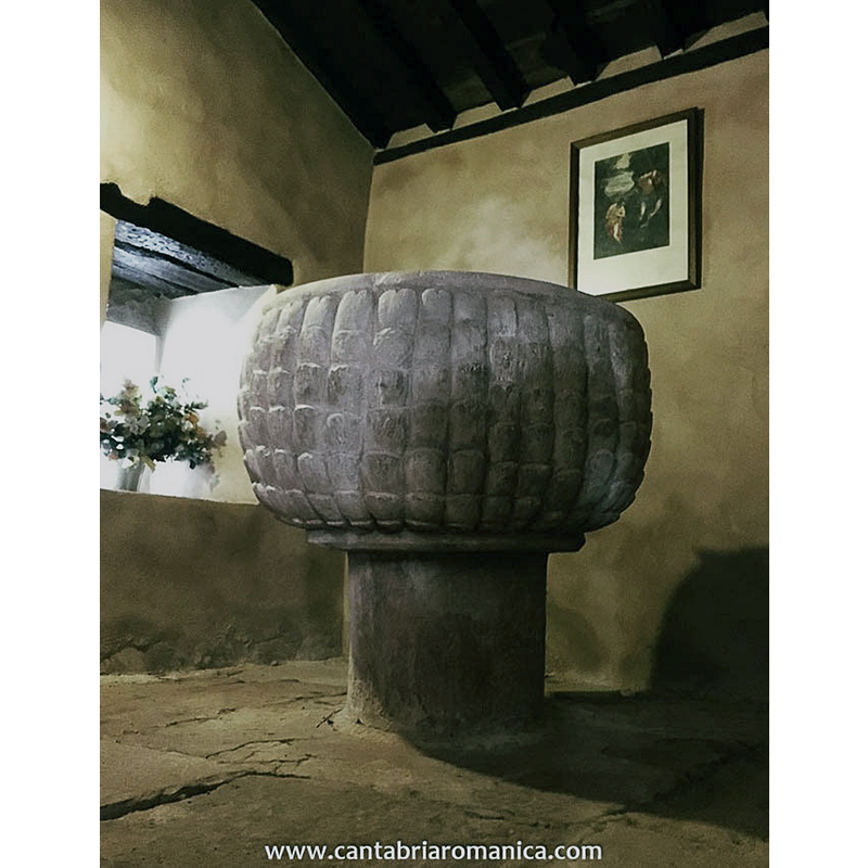 Source caption: "otro de los elementos de plena época románica que podemos encontrar en la iglesia de San Juan Bautista en Villanueva de la [Nia] es su maravillosa pila bautismal situada a la izquierda de la entrada de la iglesia. Se trata de una pila semiesférica de buen tamaño cuya cuba está decorada con escamas verticales al estilo de otra pila bautismal que podemos encontrar en Bustillo del Monte. La semejanza entre ambas pilas y el hecho de que no haya ninguna decoración parecida en todo el valle nos lleva a pensar que pudieron salir del mismo taller e incluso ser talladas por la misma mano."