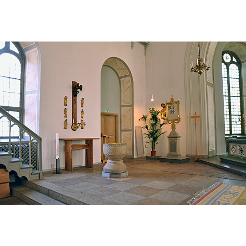 the font in the northeast corner; behind the font is the sacristy doorway; on the left is the pulpit; on the right is the altar
