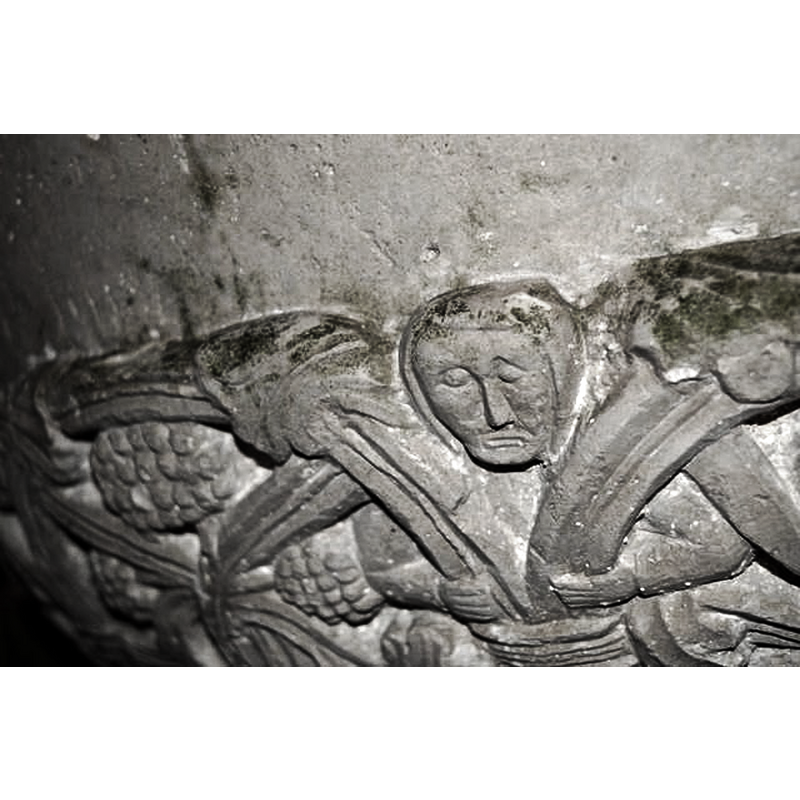 showing a human figure caught in the spandrel of the underbowl vine, with arms akimbo and the hands clasping at the stems of the vine; appears to be the only one, the rest of the spandrels filled with floral motifs