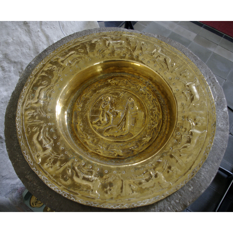 the baptismal dish of brass was made in the 16th century and has a scene of the Annunciation to Mary in the centre