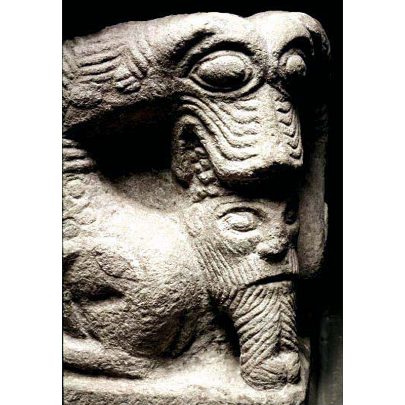 a complicated arrangement: attached to a single lion head are two bodies of rampant-regardant lions; the single head holds in its jaws the head of a bearded man; thsi carving is on the opposite angle across from the ram's head