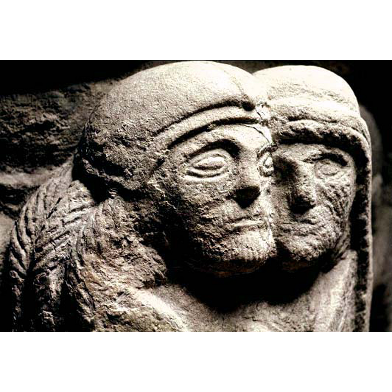 man with long braided hair on the left; woman with long hair on the right; embracing and wrapped in their cloaks or mantles