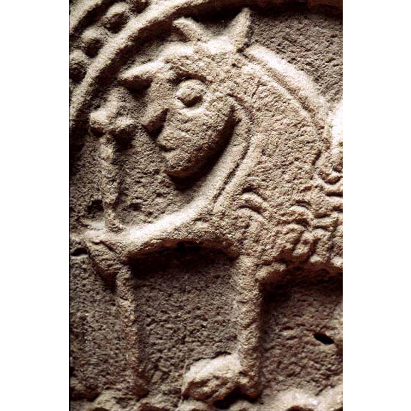 passant to the left; its font leg holds an object resembling a processional cross or a cross-topped mace, like the one held by the warrior in the fight scene