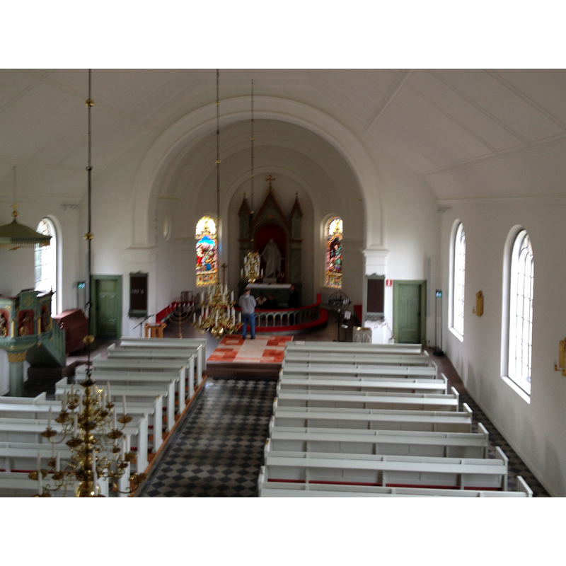 Source caption: "Svalövs kyrka inifrån." -- showing the medieval font on the right [south] side, at the far [east] end of the bank of benches