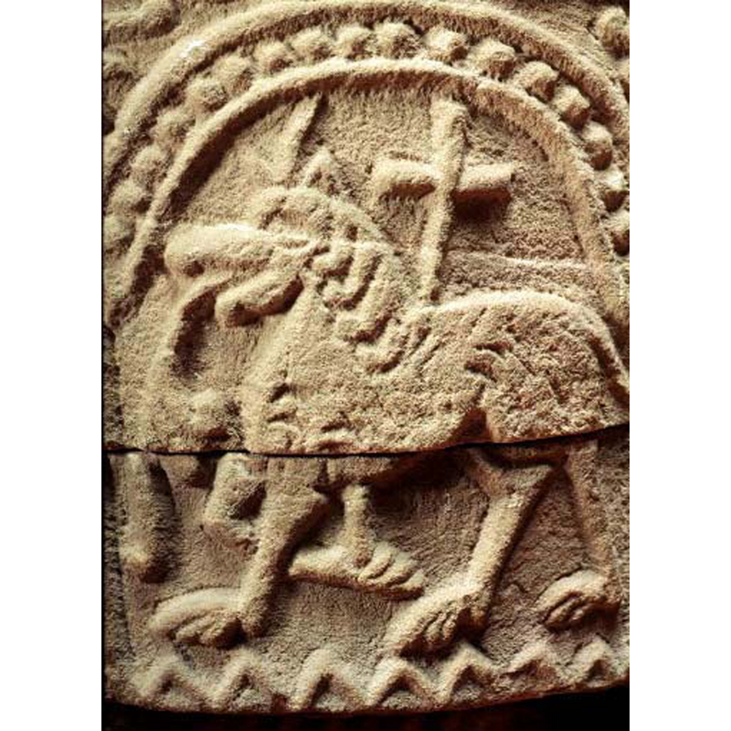passant to the left; somewhat uncharacteristic for an Agnus Dei to resemble a lion with a floriated tongue hanging down