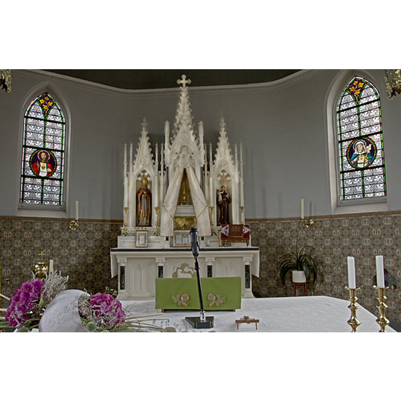 the top of the brass font is discernible below the left window, semi-hidden by the flowers
